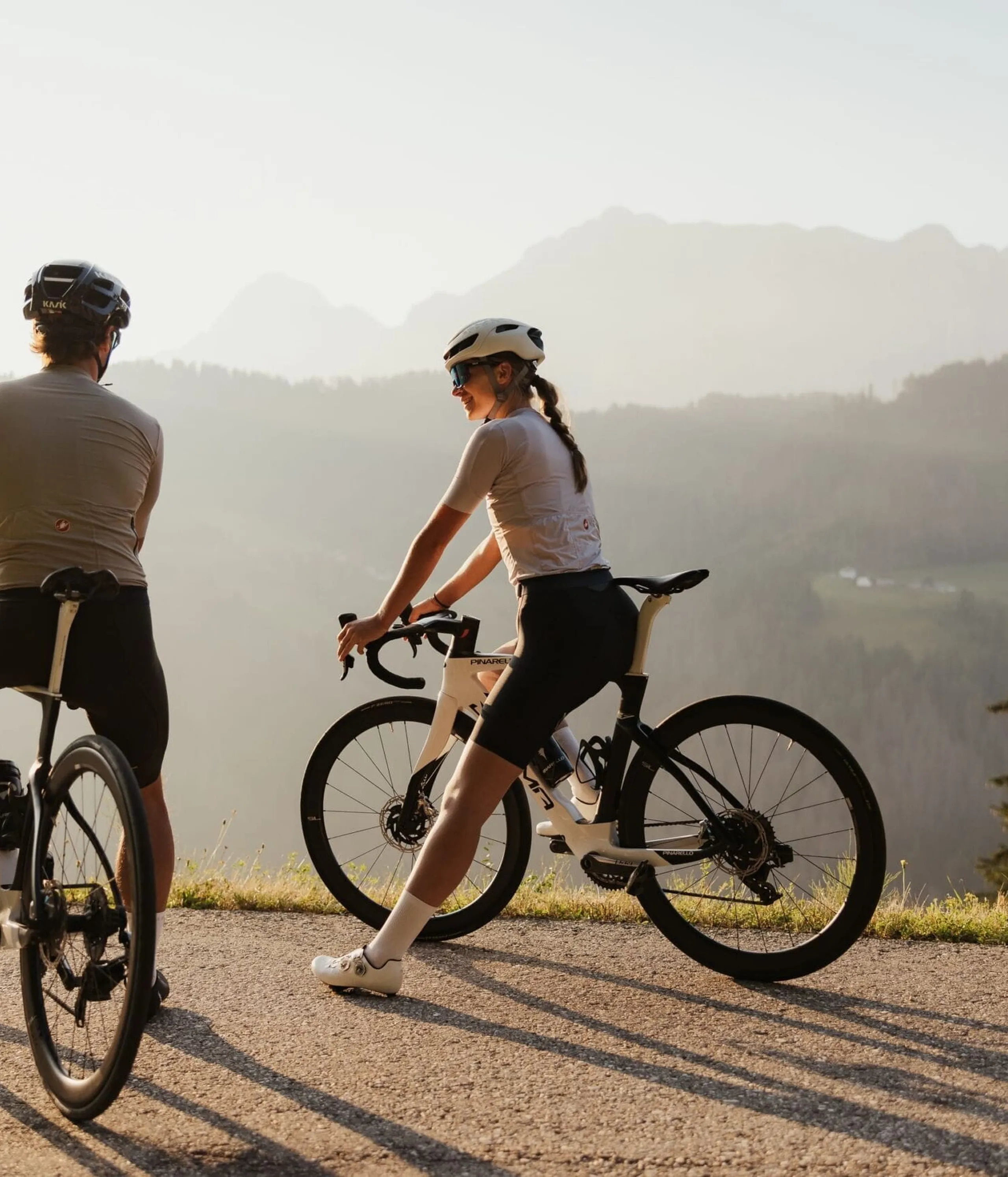two cyclists resting with scenic mountain valley backdrop at sunset in La Villa Alta Badia