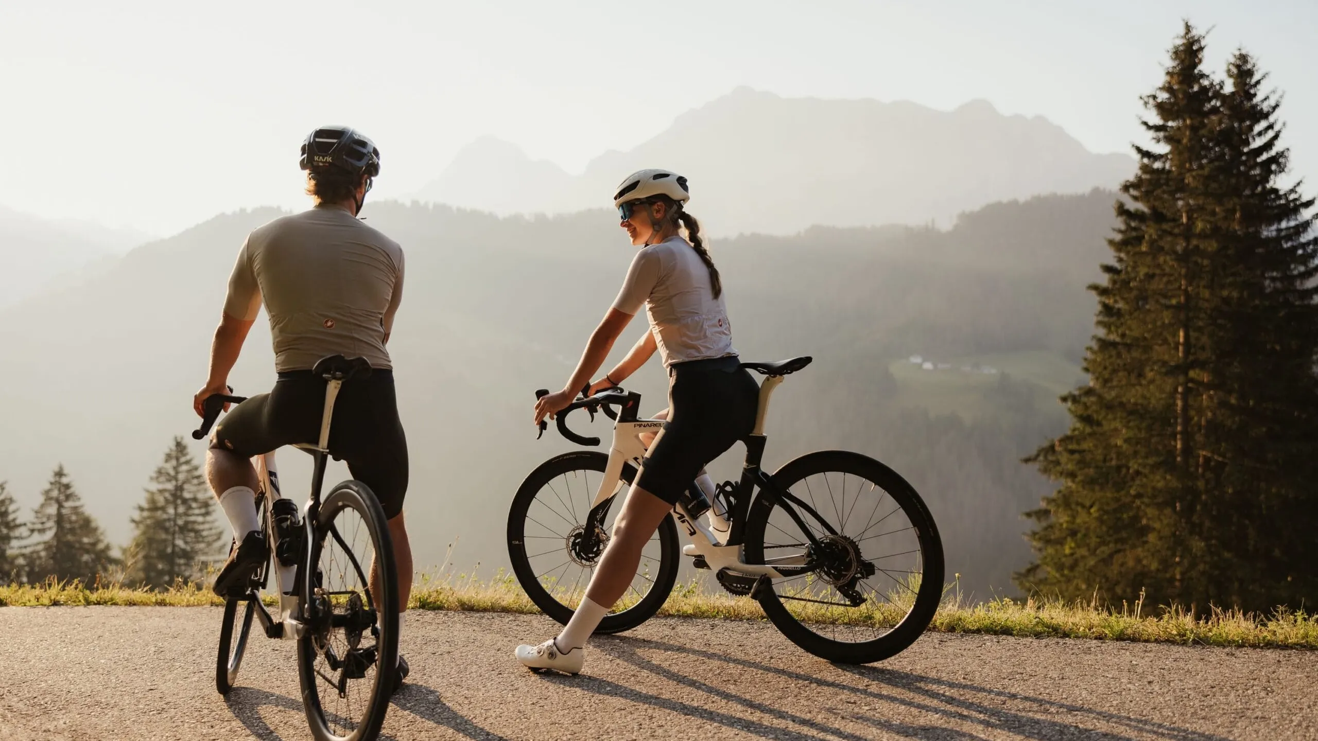 two cyclists resting with scenic mountain valley backdrop at sunset in La Villa Alta Badia
