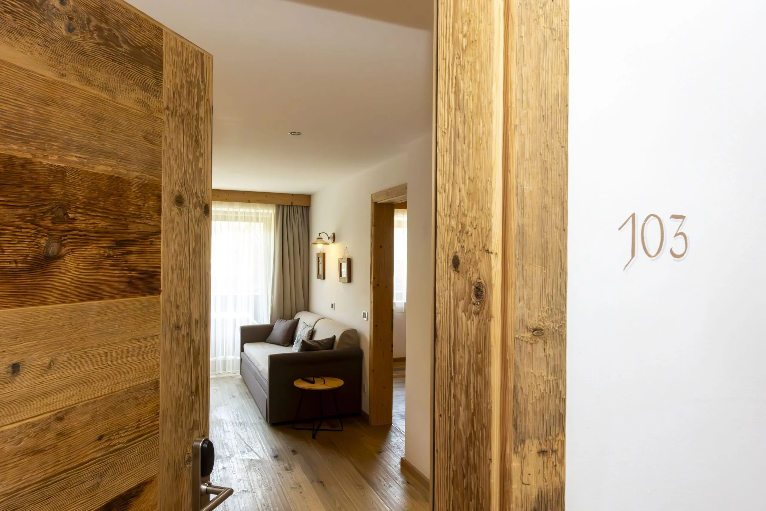 Doorway to a cozy living room with a sofa, wooden floors, and warm lighting.