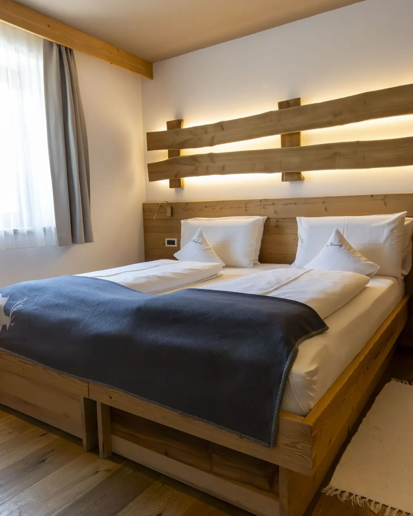 Cozy wooden hotel room with a large bed, white linens, and a backlit wooden headboard.