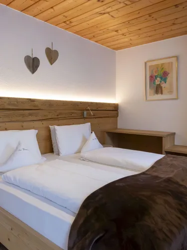Cozy wooden bedroom with a large bed, white linens, brown throw, and built-in wardrobe in warm lighting