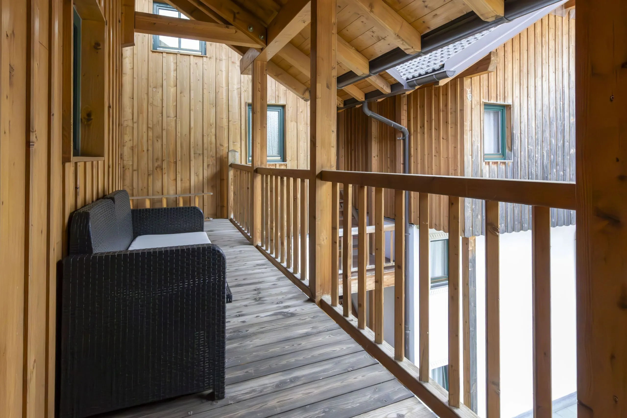 Wooden balcony with wicker seating, railings, and cabin-style walls in Alta Badia.