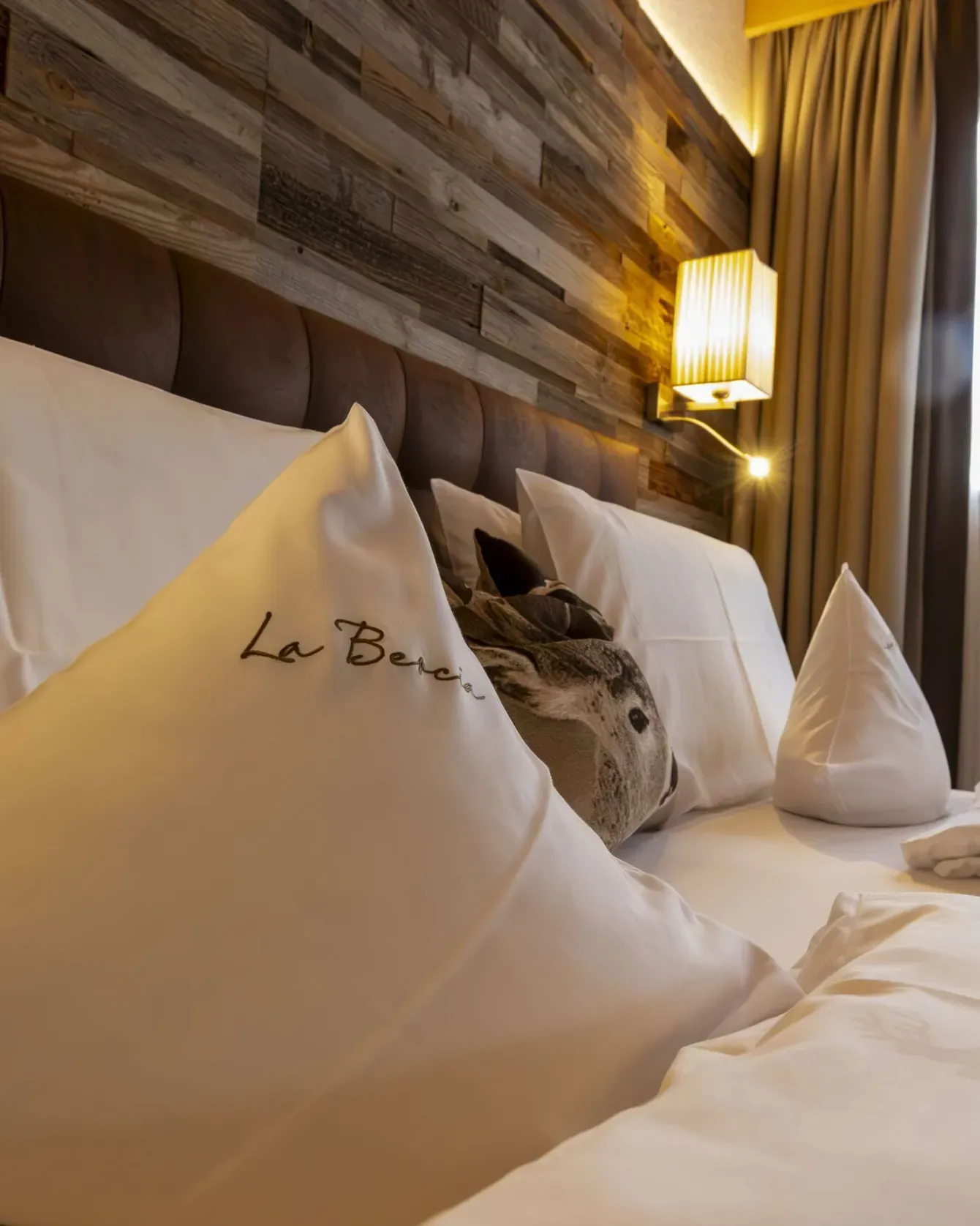 Luxurious hotel bed with white linens and decorative pillows in a warmly lit bedroom.