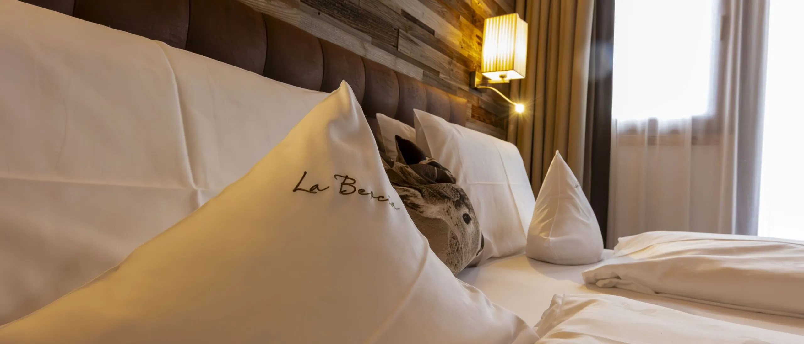 Luxurious hotel bed with white linens and decorative pillows in a warmly lit bedroom.