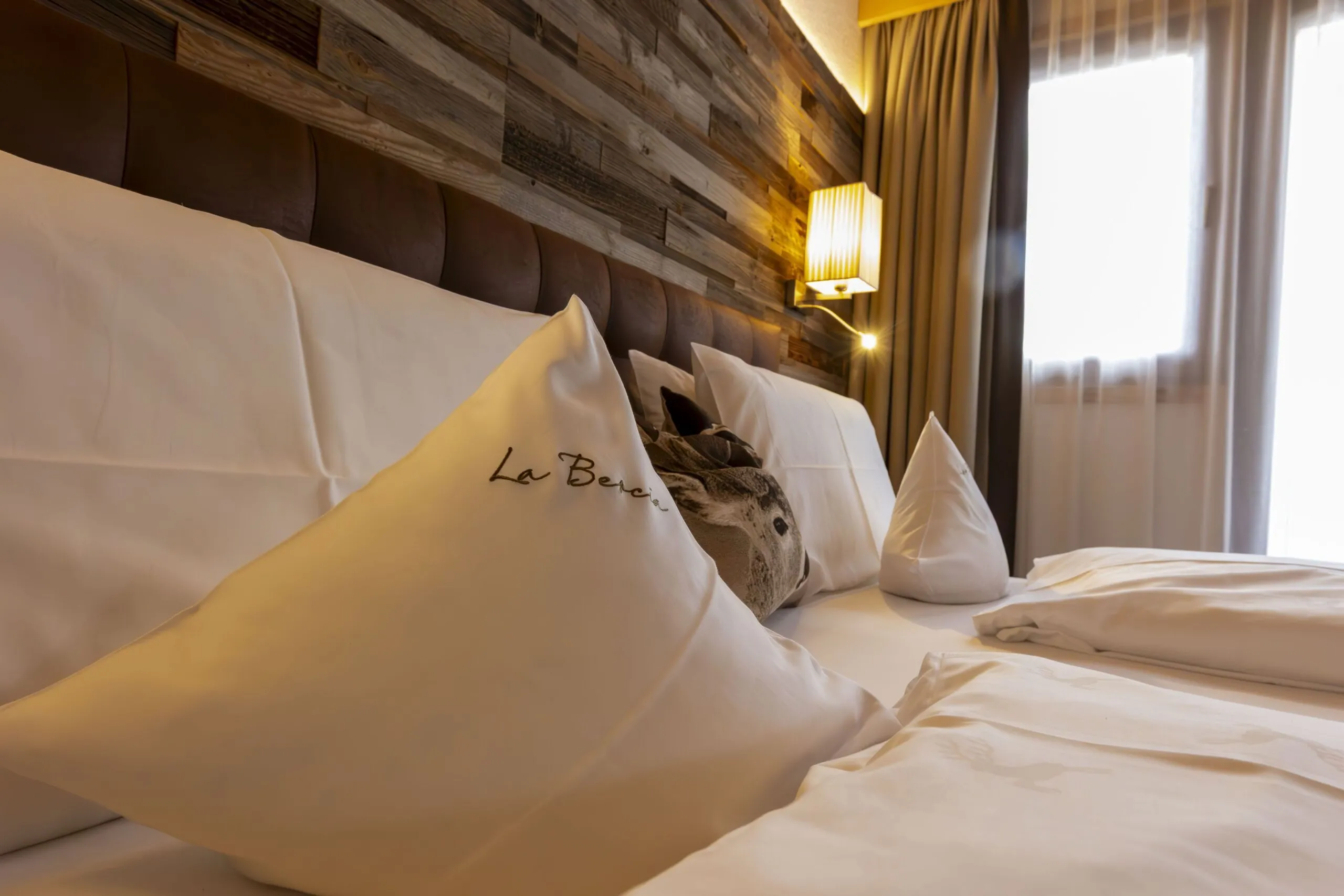 Luxurious hotel bed with white linens and decorative pillows in a warmly lit bedroom.