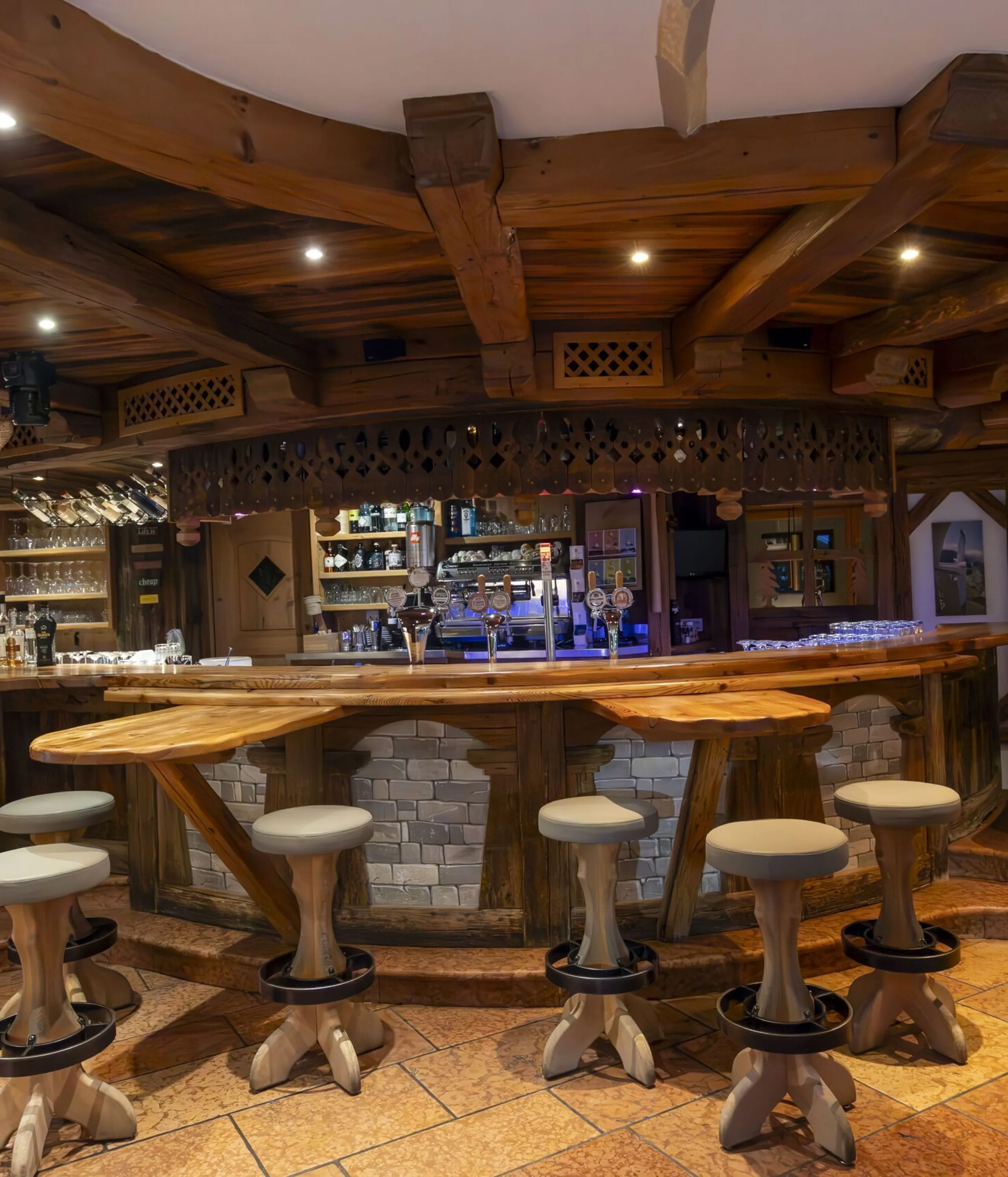 Cozy wooden bar interior with rustic stools, warm lighting, and stone front at La Villa venue.