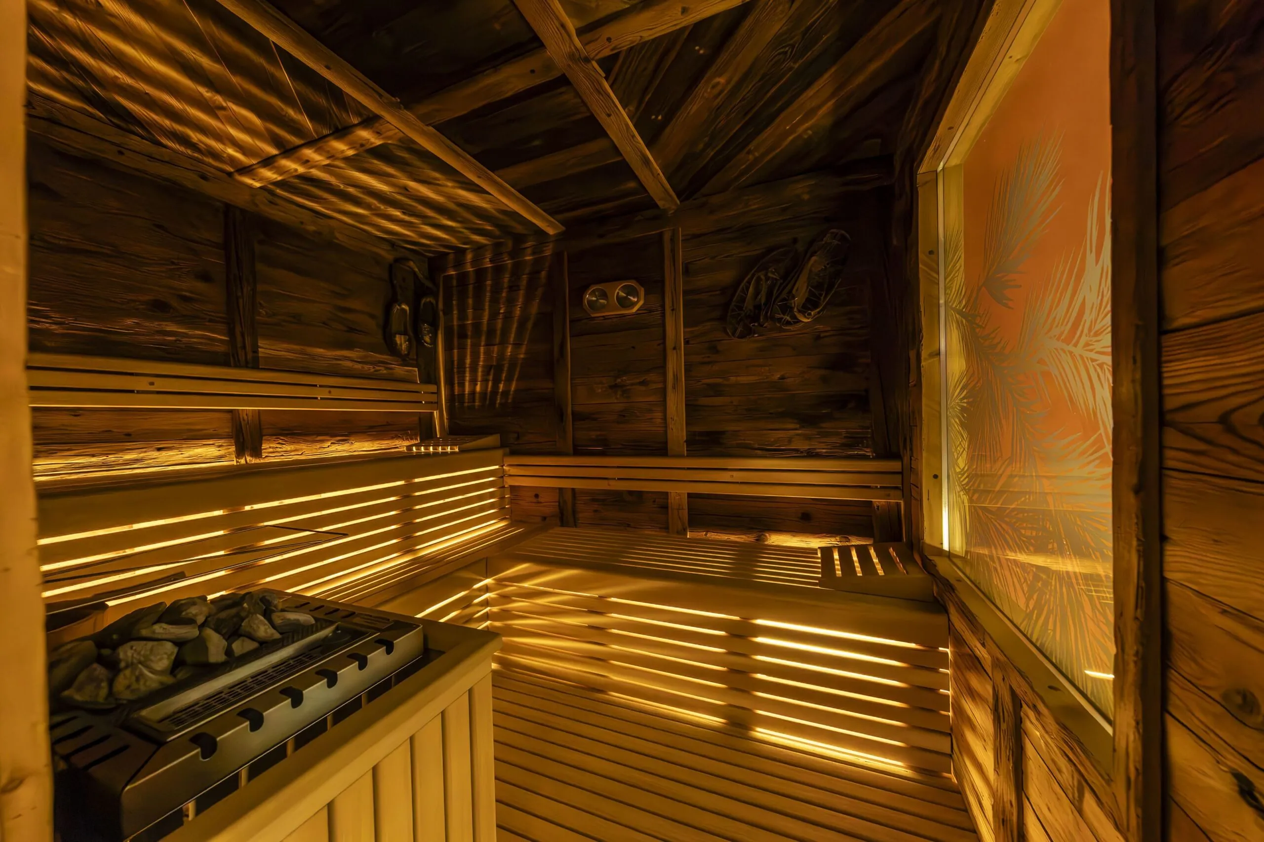 Cozy wooden sauna interior with benches, heater stones, and warm ambient lighting in La Villa (La Bercia).